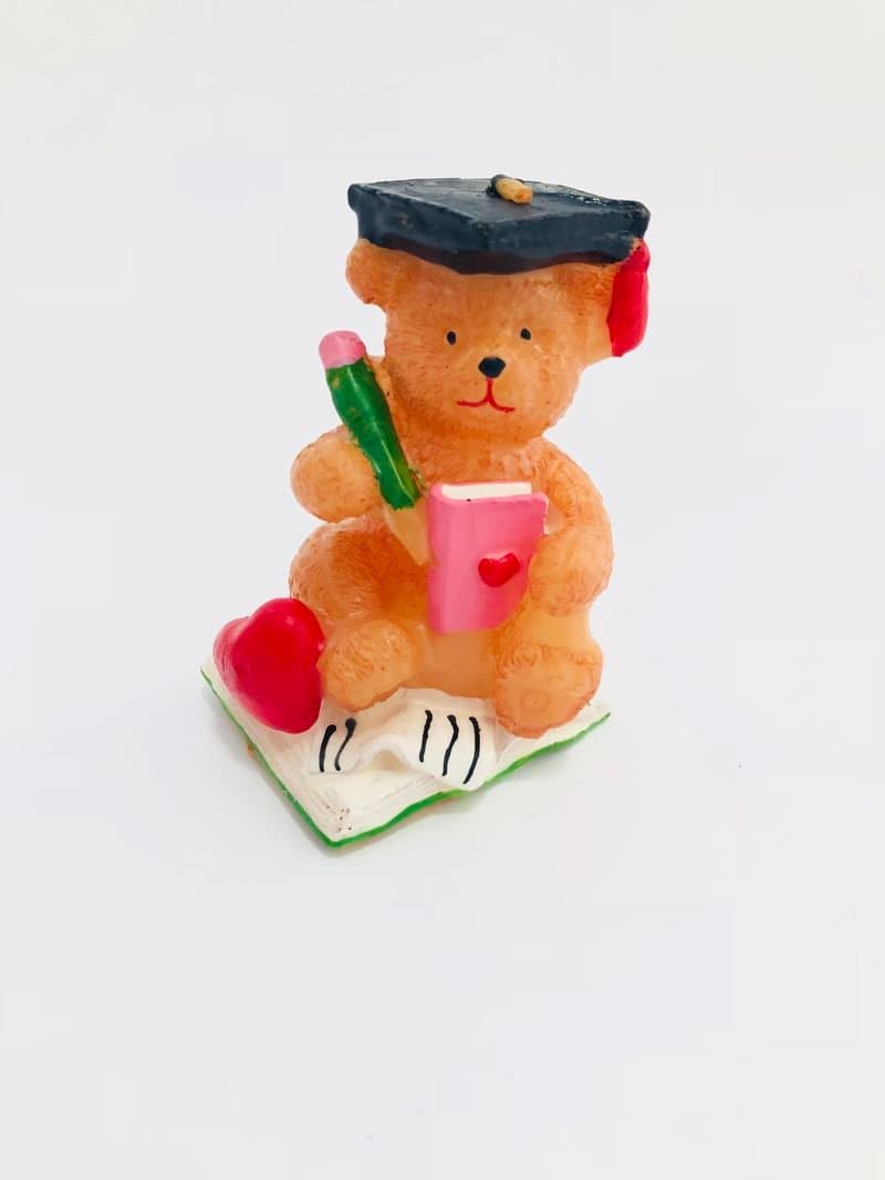 Мече с шапка за завършване, държащо молив и телефон, със сърца и книга, подходящо за тематични парти или като декорация за празници.